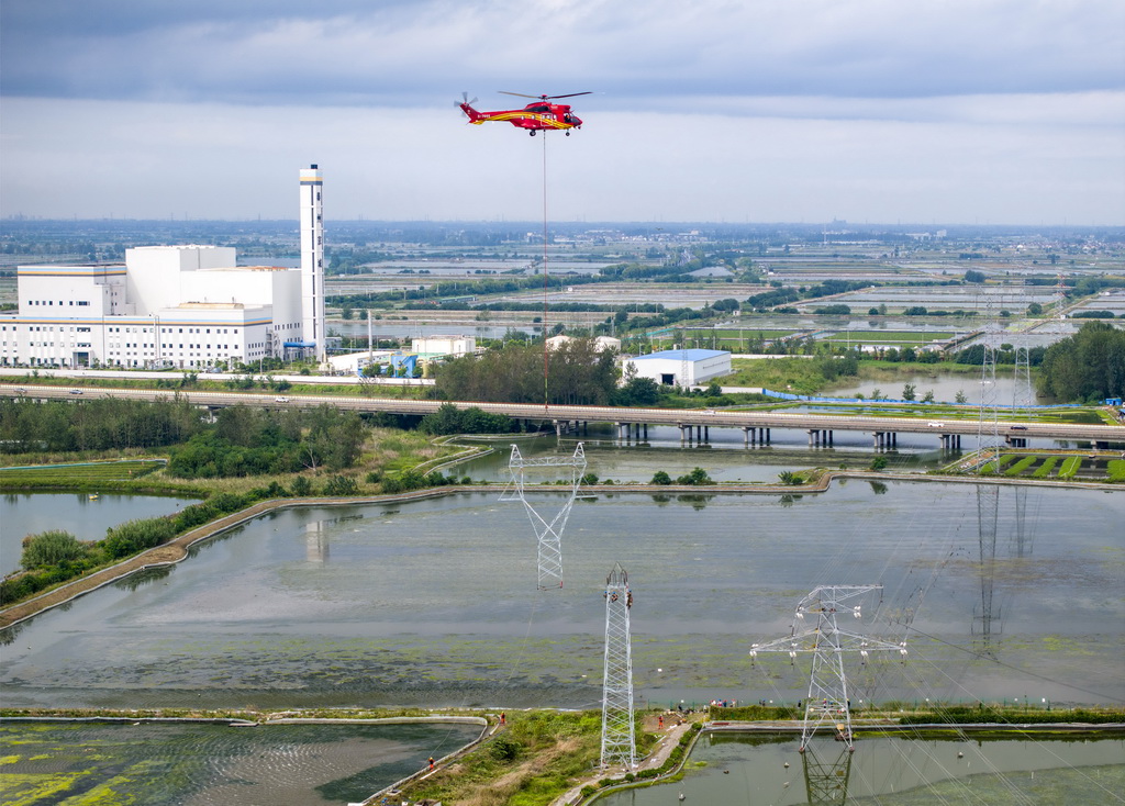 9月24日，直升機(jī)在江蘇省興化市昌榮鎮(zhèn)上空協(xié)助鐵塔架設(shè)作業(yè)（無(wú)人機(jī)照片）。新華社發(fā)（湯德宏攝）