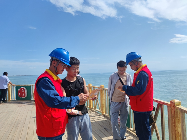 6月23日，國網(wǎng)博湖縣供電公司員工巴音達(dá)來、阿力米熱提·阿不都熱合曼為開湖季捕魚節(jié)開幕保點(diǎn)護(hù)航，向游客發(fā)放安全用電手冊。（王坤） (3)_副本.jpg