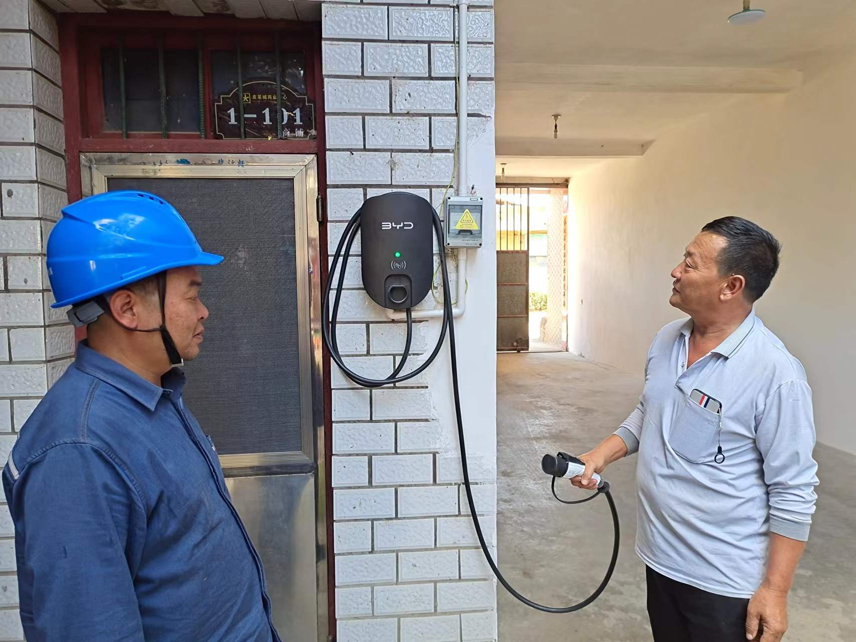 3、客戶手里拿著通電的充電樁，高興對工作人員表示感謝。.jpg